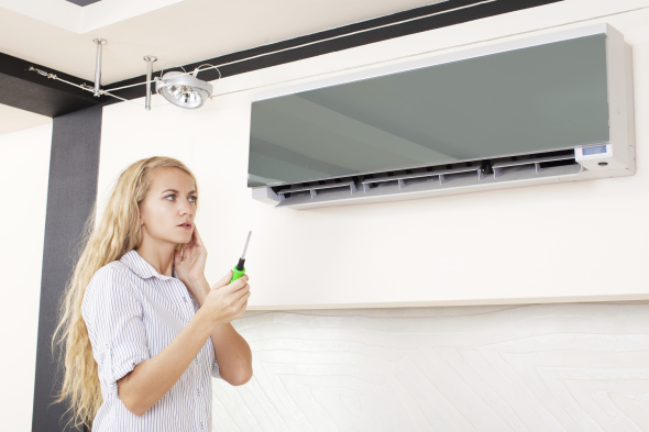 Woman looks at a broken air conditioner